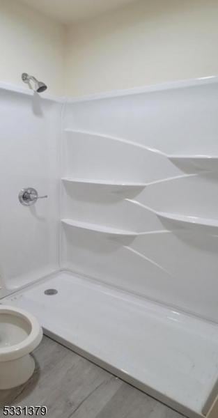 bathroom with a shower, toilet, and hardwood / wood-style flooring