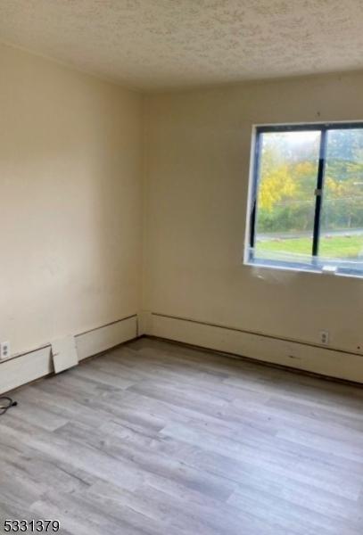 spare room featuring a textured ceiling and light hardwood / wood-style floors