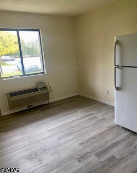 spare room featuring a textured ceiling, light wood-type flooring, and a wall mounted AC