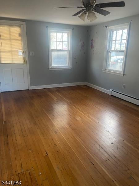 empty room with hardwood / wood-style floors, ceiling fan, and a baseboard radiator