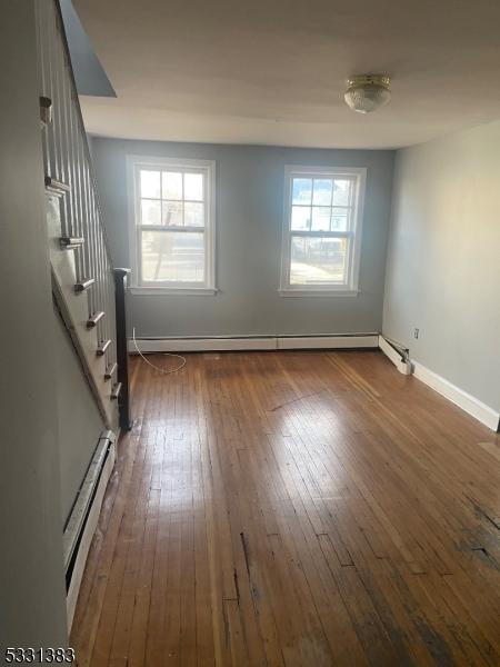 unfurnished room with dark hardwood / wood-style floors, a baseboard radiator, and a healthy amount of sunlight