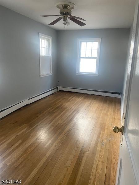 spare room featuring ceiling fan, hardwood / wood-style floors, and a baseboard radiator