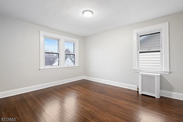 spare room with radiator heating unit and dark wood-type flooring