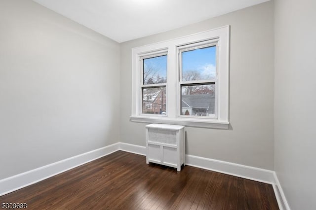 spare room with dark hardwood / wood-style flooring and radiator heating unit