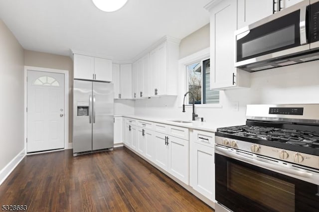 kitchen with appliances with stainless steel finishes, dark hardwood / wood-style flooring, white cabinetry, and sink