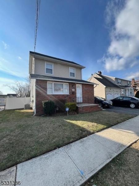 view of front of home with a front lawn and central air condition unit