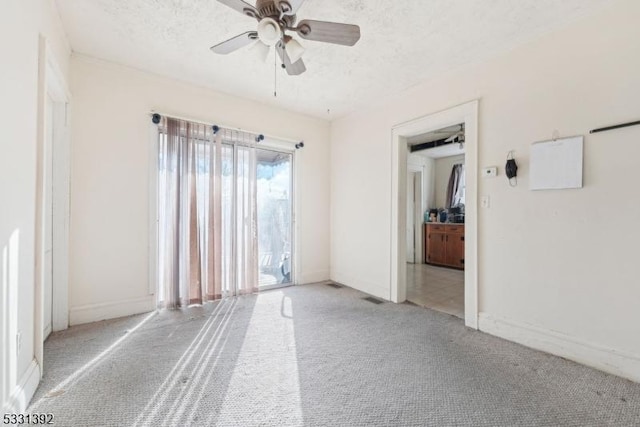 empty room with a textured ceiling, ceiling fan, and light colored carpet