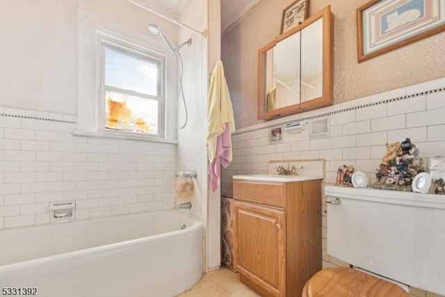 full bathroom featuring toilet, vanity, tile walls, and tiled shower / bath combo