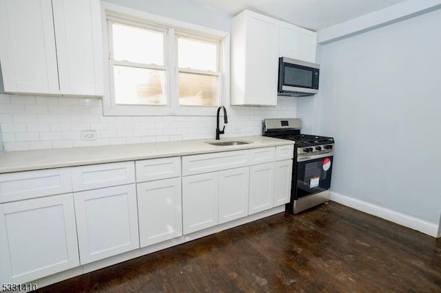 kitchen with white cabinetry, sink, dark hardwood / wood-style floors, decorative backsplash, and appliances with stainless steel finishes