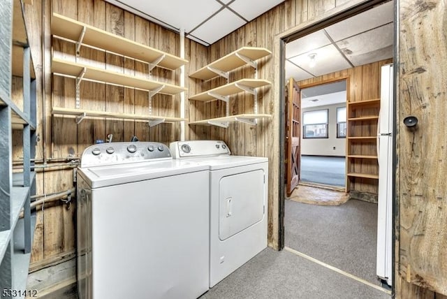 laundry room with laundry area, independent washer and dryer, and wood walls