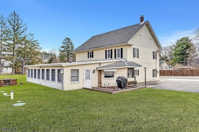 rear view of house featuring a patio area, a lawn, a chimney, and fence