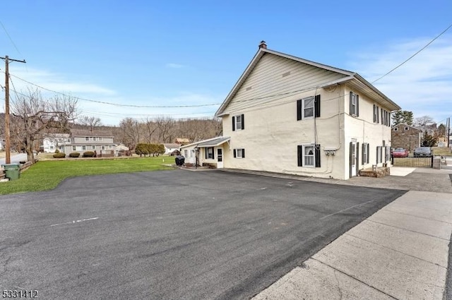 view of property exterior with aphalt driveway and a yard