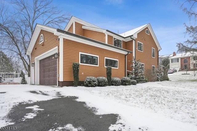 snow covered property with a garage