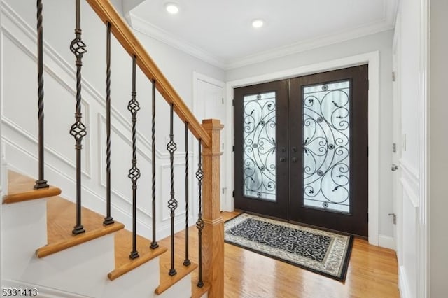 foyer entrance featuring light wood-type flooring, crown molding, and french doors