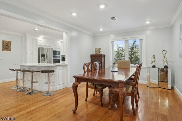 dining space with crown molding and light wood-type flooring