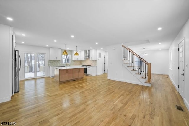 unfurnished living room with light wood-type flooring and an inviting chandelier