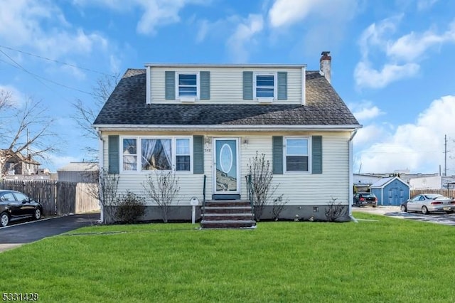 bungalow-style home with entry steps, roof with shingles, fence, and a front yard