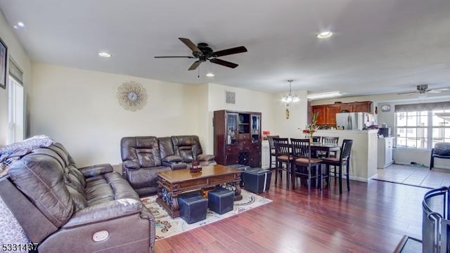 living room with ceiling fan with notable chandelier and dark hardwood / wood-style floors