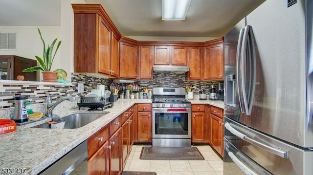 kitchen featuring backsplash, sink, light tile patterned flooring, light stone counters, and stainless steel appliances