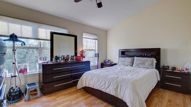 bedroom with ceiling fan, light hardwood / wood-style floors, and lofted ceiling