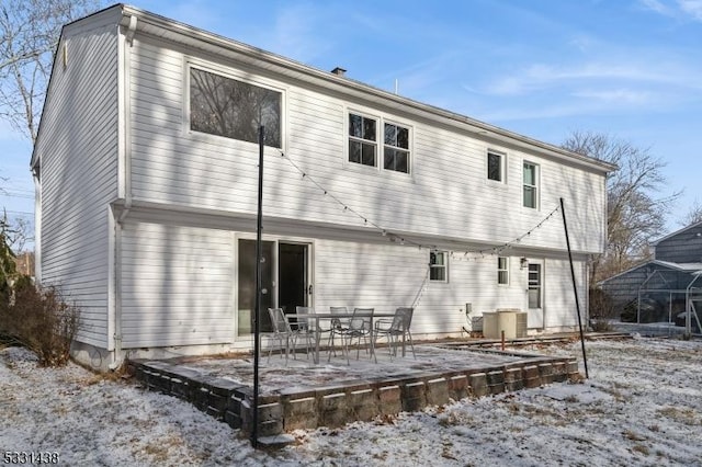 snow covered rear of property featuring cooling unit