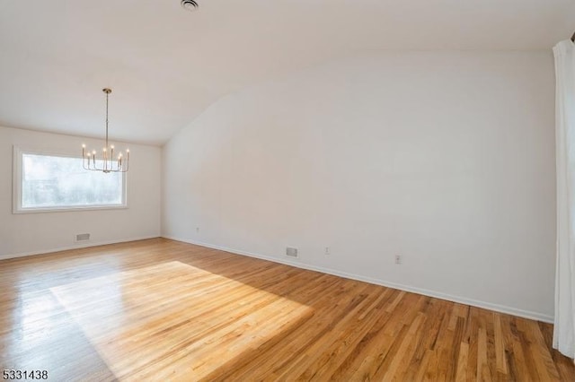 unfurnished room with a notable chandelier, light hardwood / wood-style floors, and lofted ceiling