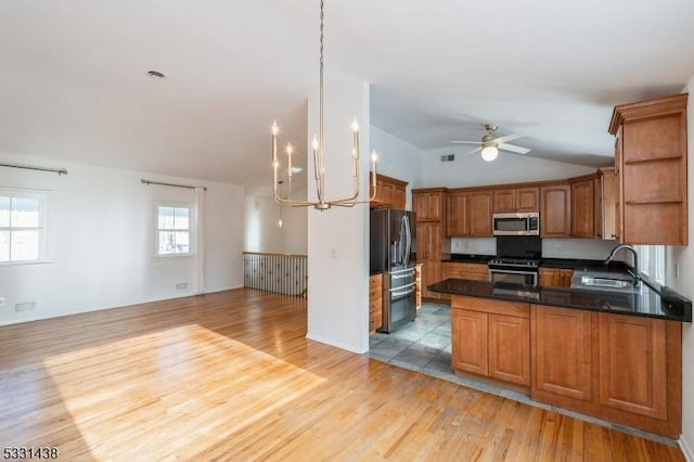 kitchen featuring kitchen peninsula, appliances with stainless steel finishes, ceiling fan with notable chandelier, sink, and hanging light fixtures