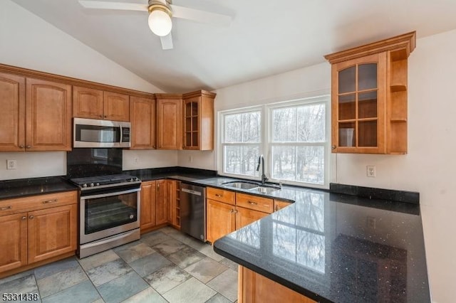 kitchen featuring ceiling fan, sink, dark stone counters, lofted ceiling, and appliances with stainless steel finishes