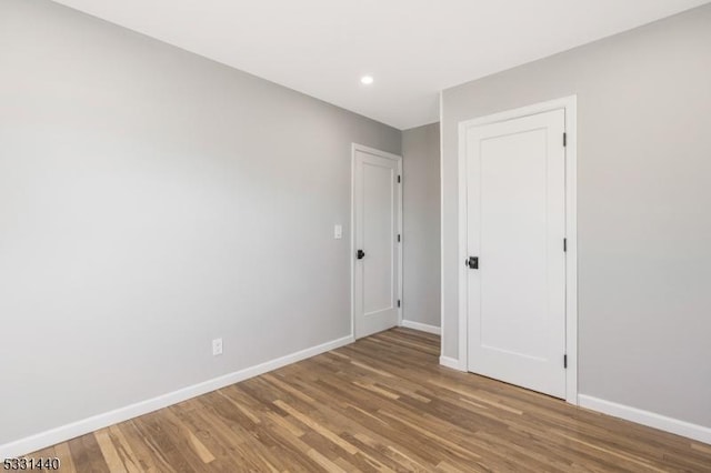 unfurnished bedroom with recessed lighting, baseboards, and wood finished floors