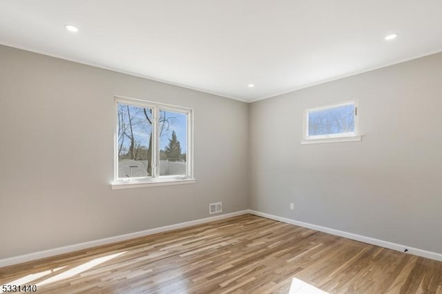 spare room featuring light wood-type flooring, baseboards, visible vents, and recessed lighting