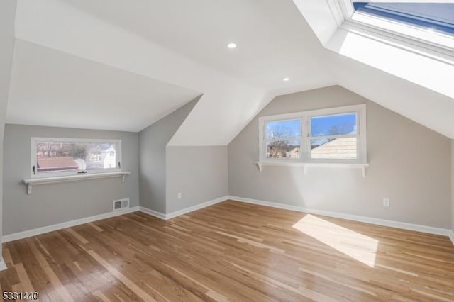 bonus room featuring a wealth of natural light, vaulted ceiling with skylight, visible vents, and wood finished floors