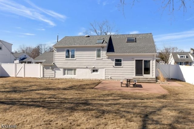 rear view of house featuring entry steps, a patio, a fenced backyard, roof with shingles, and a yard