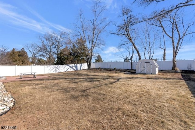 view of yard with a fenced backyard, an outdoor structure, and a shed