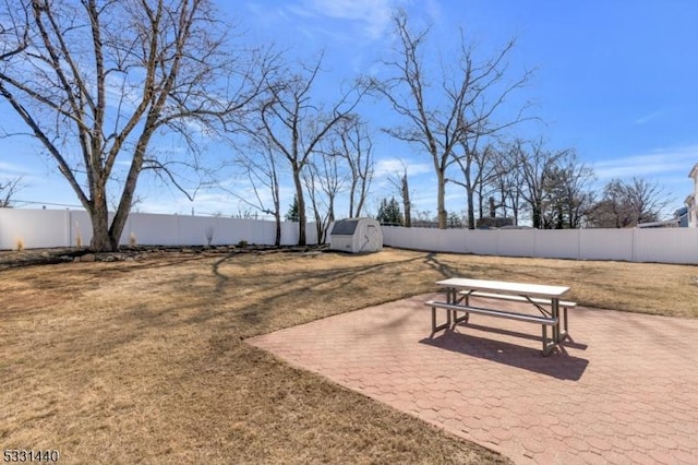 view of property's community featuring a fenced backyard, an outdoor structure, a patio, and a storage unit