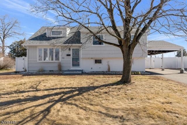 view of front facade with a shingled roof, fence, a carport, and a front yard