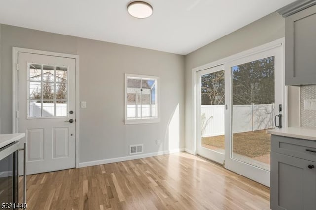 doorway featuring beverage cooler, visible vents, baseboards, and light wood finished floors