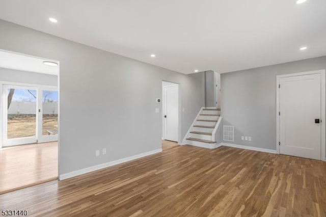 unfurnished living room featuring baseboards, visible vents, wood finished floors, stairs, and recessed lighting