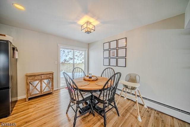 dining area featuring a baseboard radiator and light hardwood / wood-style flooring