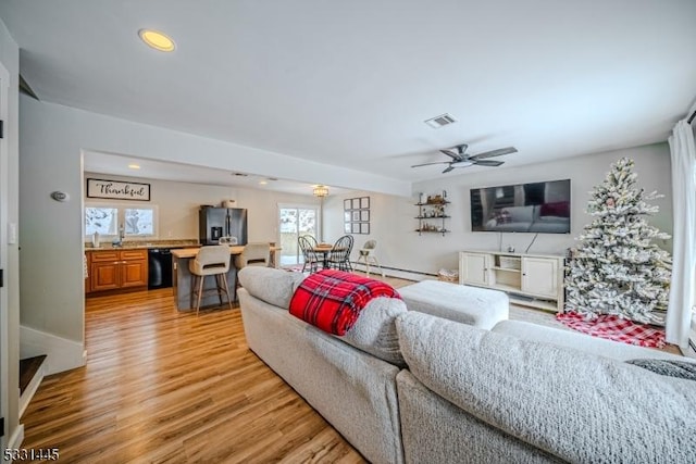 living room featuring ceiling fan, baseboard heating, and light hardwood / wood-style flooring