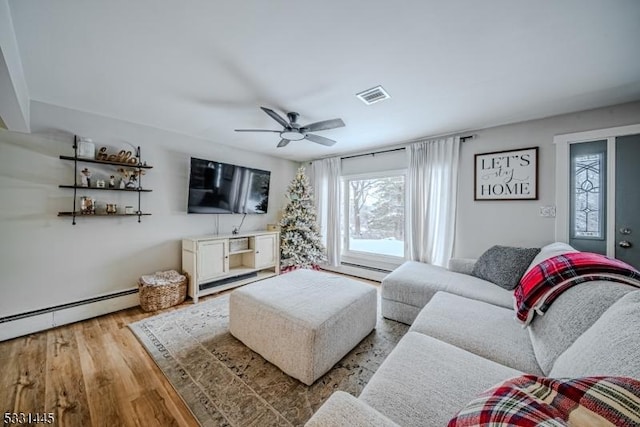 living room with light hardwood / wood-style floors, baseboard heating, and ceiling fan