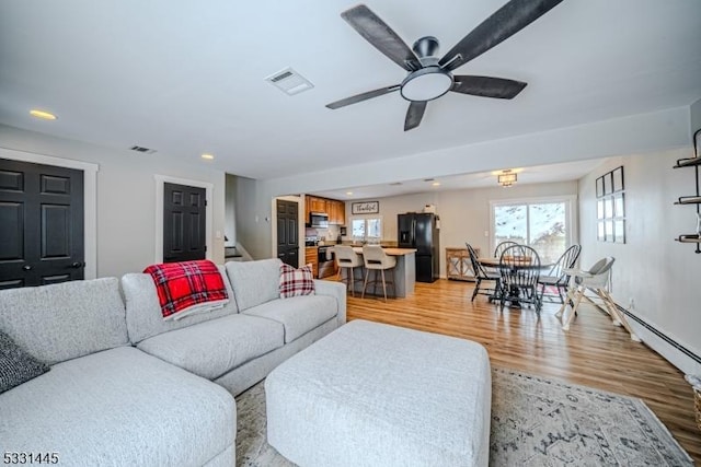 living room with light hardwood / wood-style flooring and ceiling fan