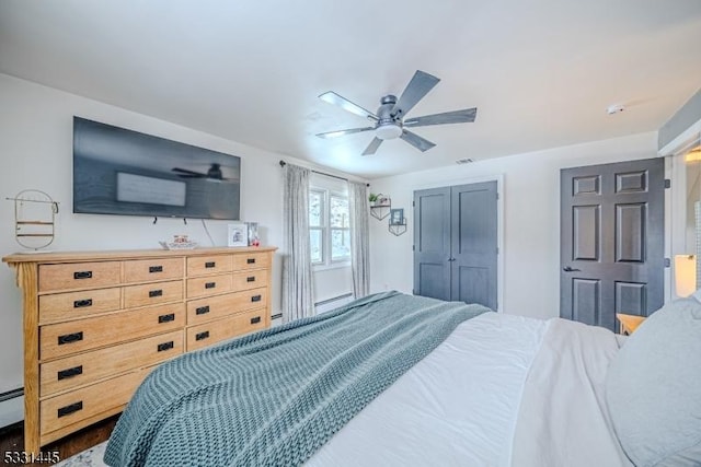 bedroom with ceiling fan, a closet, and a baseboard heating unit