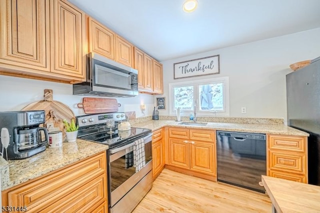 kitchen featuring appliances with stainless steel finishes, light hardwood / wood-style floors, light stone counters, and sink