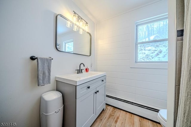 bathroom with toilet, vanity, a baseboard radiator, and wood-type flooring