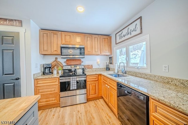 kitchen with light stone counters, light hardwood / wood-style floors, sink, and stainless steel appliances