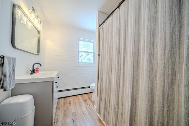 bathroom featuring vanity, hardwood / wood-style flooring, toilet, and a baseboard heating unit