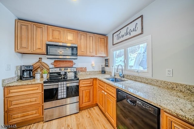 kitchen with light stone counters, sink, light hardwood / wood-style flooring, and appliances with stainless steel finishes