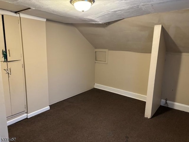 bonus room with a textured ceiling, dark carpet, and lofted ceiling