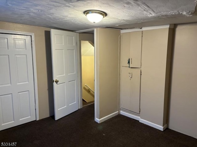 unfurnished bedroom featuring a textured ceiling and dark colored carpet