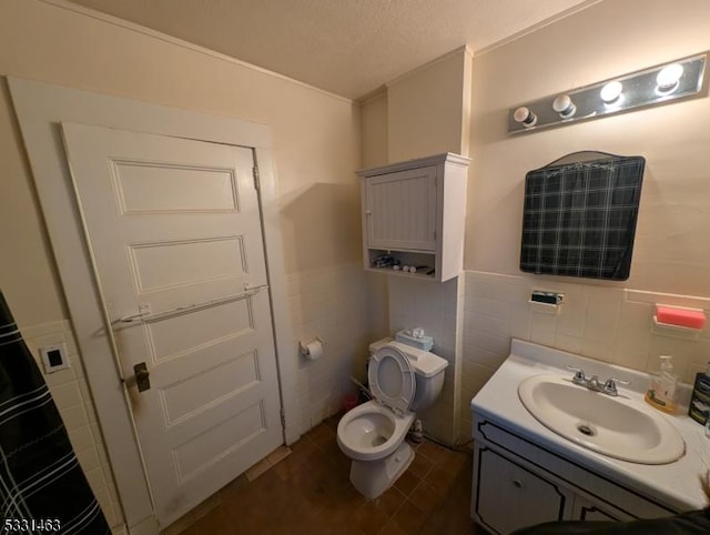 bathroom featuring a textured ceiling, vanity, toilet, and tile walls